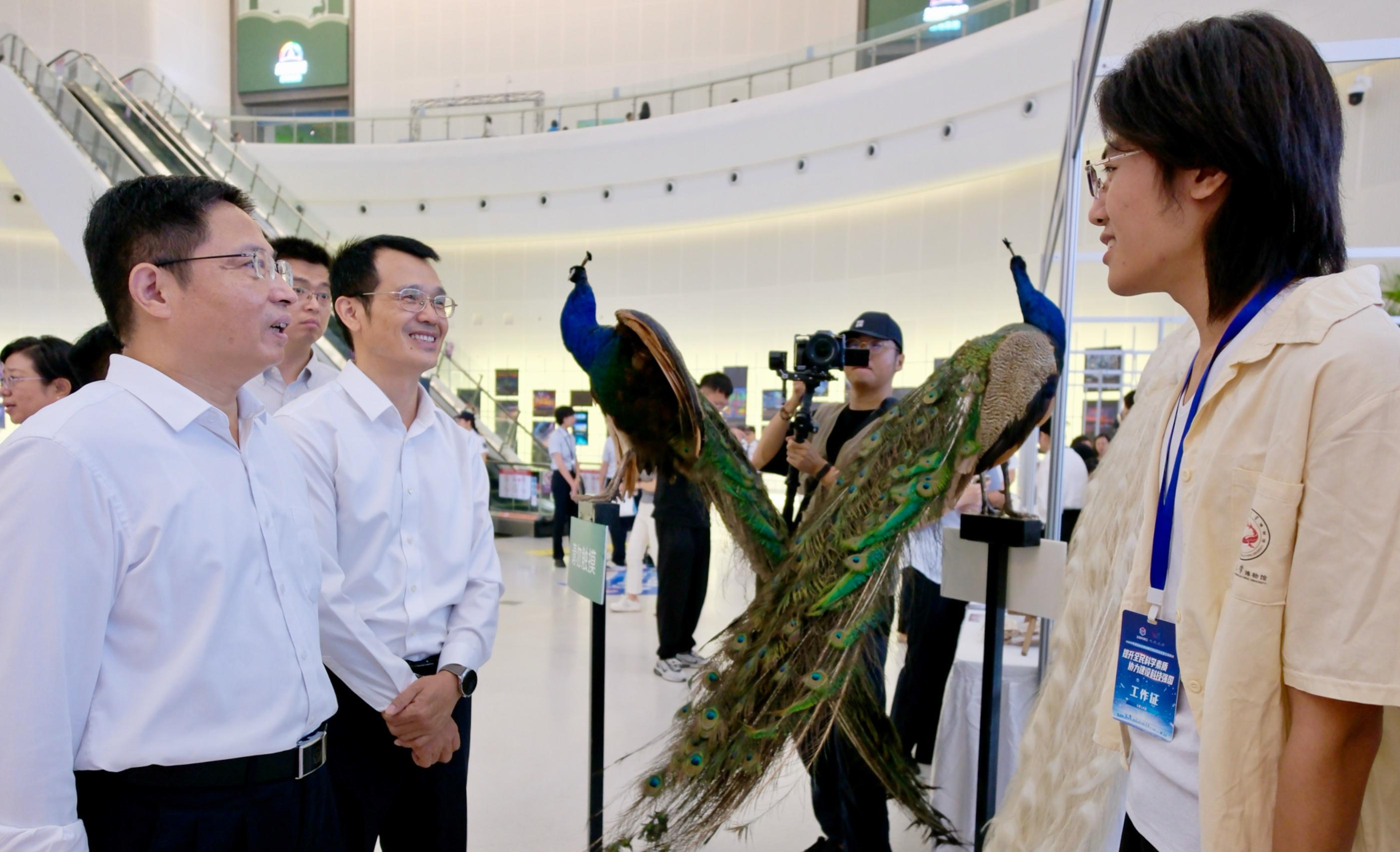 出席主場活動的領(lǐng)導(dǎo)與科普展示區(qū)的科技工作者親切交談